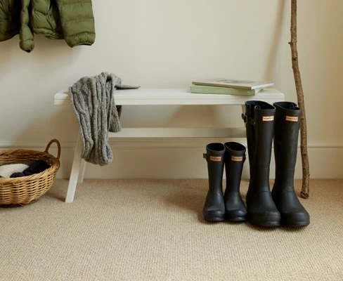Beige wool carpet in a mudroom with rubber boots