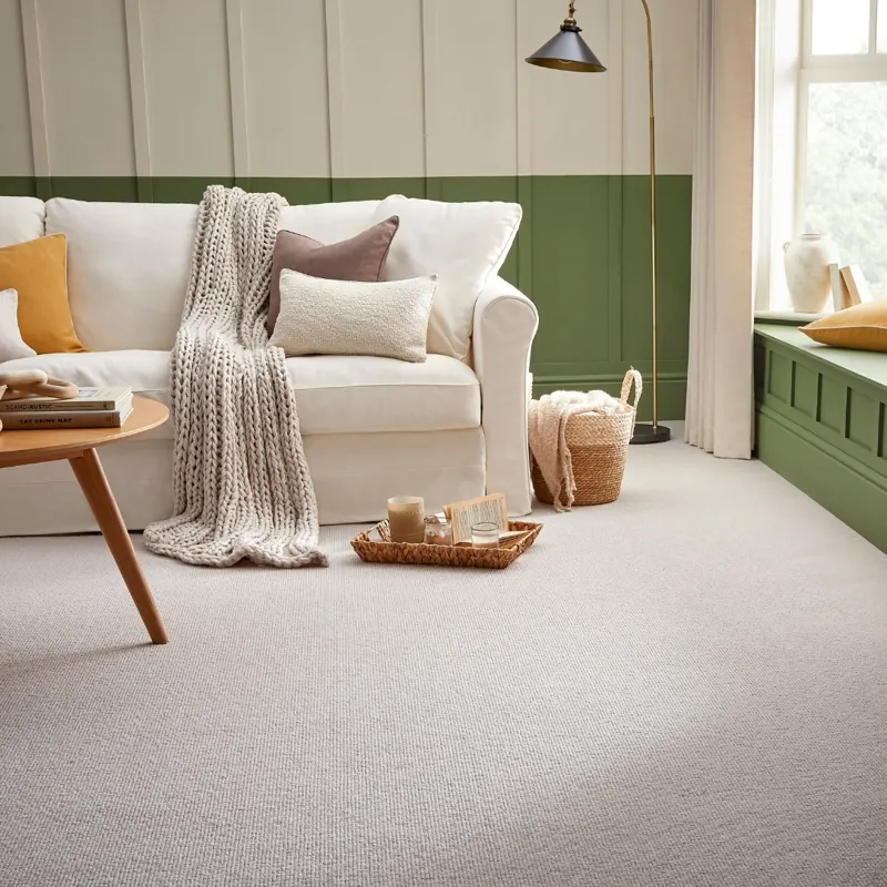 Neutral textured loop pile carpet in a cozy living room with green accents.