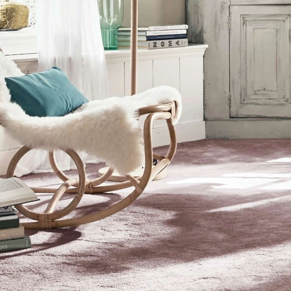 Plush mauve wool carpet in a sunlit room with a rattan chair.