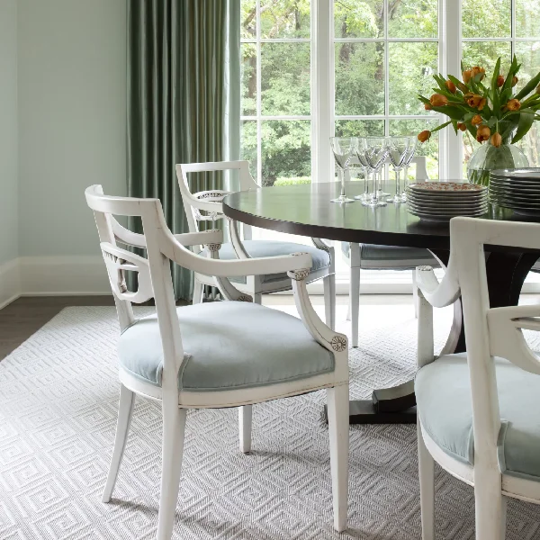 light grey diamond-patterned wool carpet under a wooden table and white chairs